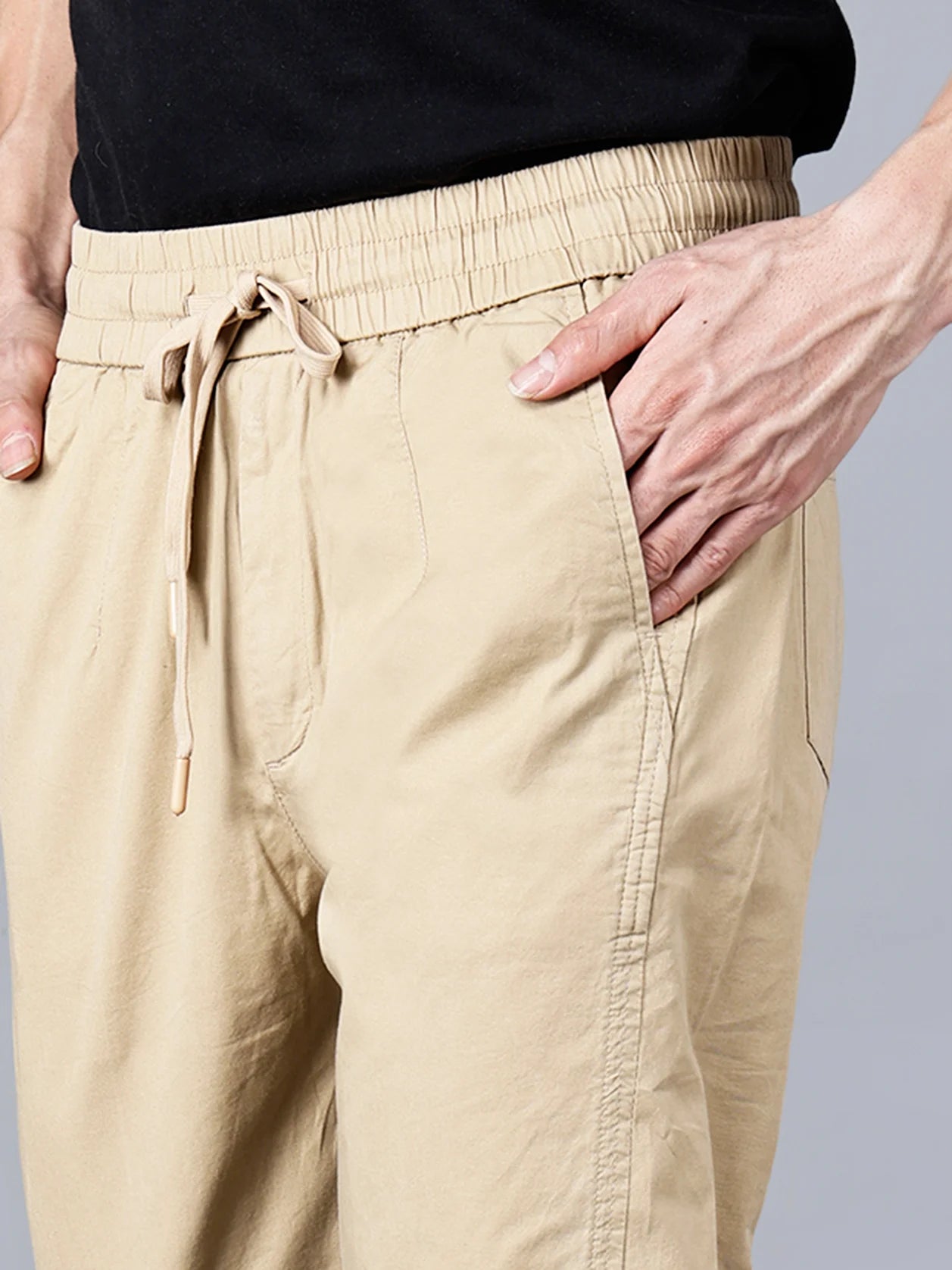 Men's Beige Cotton Track Pant from Fort Collins, featuring an elastic waistband and drawstring closure for optimal comfort. This versatile pant boasts a clean and tapered fit, along with multiple pockets for added convenience. Shop now online from anywhere in India for this stylish and breathable casual wear option.