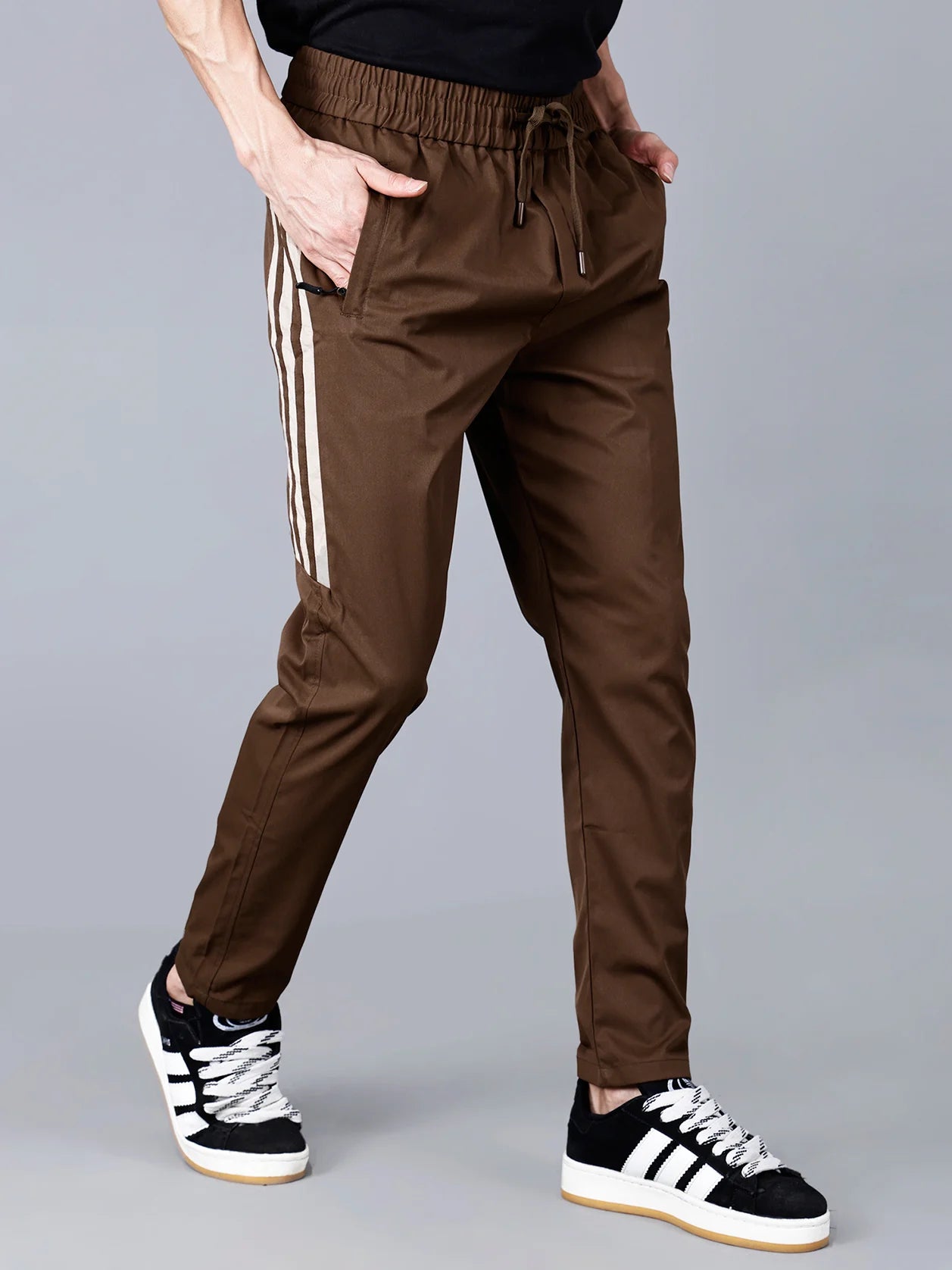 Shop our Men's Brown Slim Fit Track Pant with Side Stripes from Fort Collins. These pants are designed with zip pockets and a drawstring waist for comfort and convenience, making them perfect for workouts or casual wear. Available for purchase online in India.