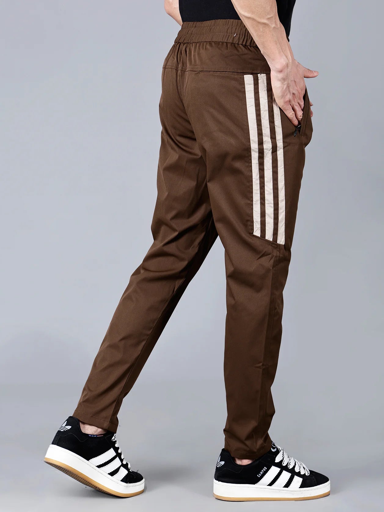 Enhance your athletic wardrobe with our Men's Brown Track Pant featuring stylish beige side stripes and a slim fit design. Stay organized with convenient zip pockets and enjoy a comfortable fit with a drawstring waist. Available for online purchase in India.