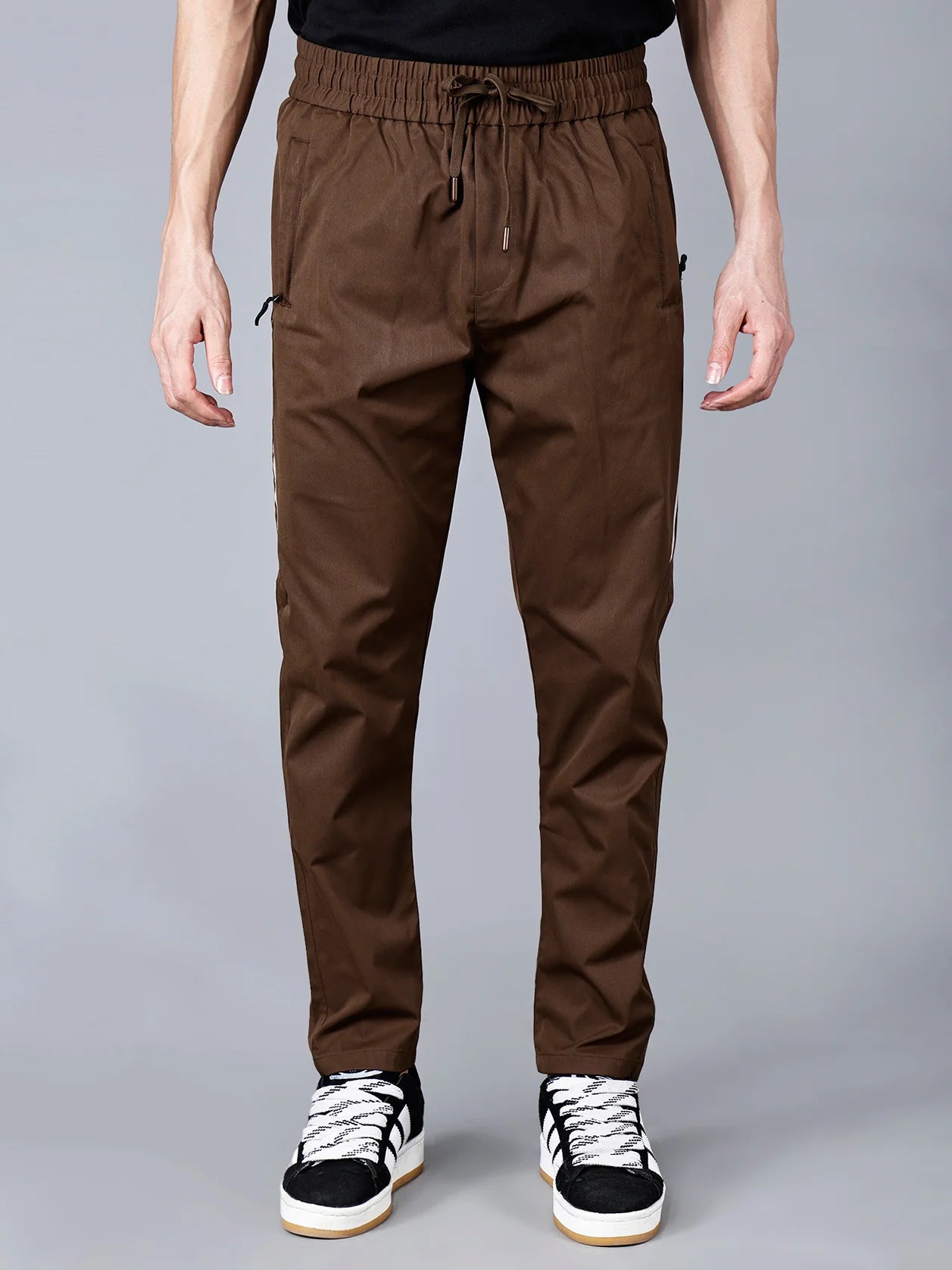 Discover the Men's Brown Slim Fit Track Pant with Side Stripes from Fort Collins. This high-quality pant features convenient zip pockets and a comfortable drawstring waist, making it ideal for both workouts and casual wear. Available for purchase online from anywhere in India.