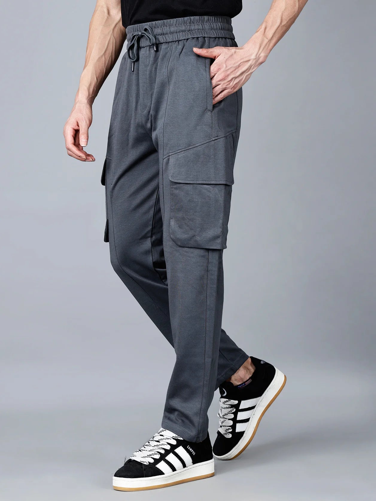 Shop now for the Men's Charcoal Grey Cargo Track Pant with Utility Pockets, featuring an elastic waistband, cargo flap pockets, and a structured cotton-polyester fabric for all-day comfort and streetwear-ready style. Available for purchase online from anywhere in India.