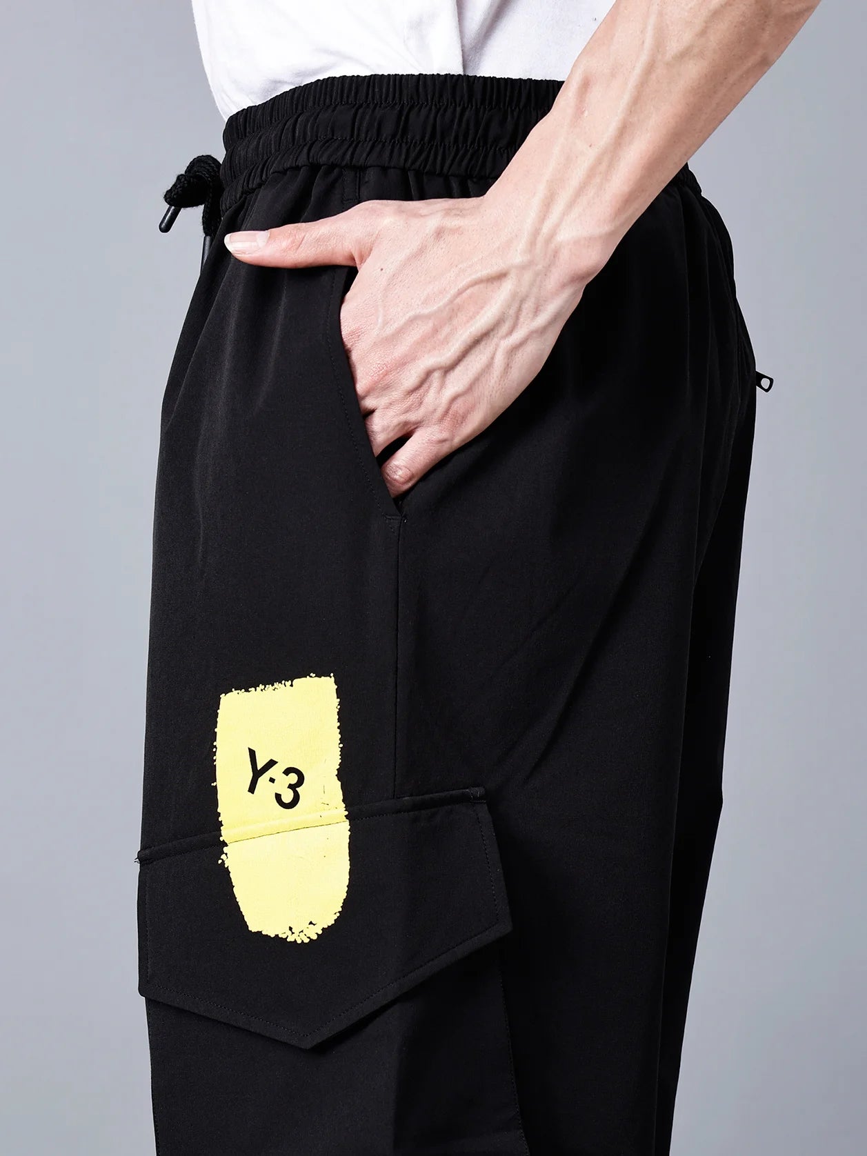 Experience the versatility and style of black cargo track pants for men featuring a Y-3 yellow patch and a bold, multicolor brushstroke print. These fashionable and relaxed fit pants are perfect for the gym, travel, and streetwear. Shop now online and have them delivered across India.
